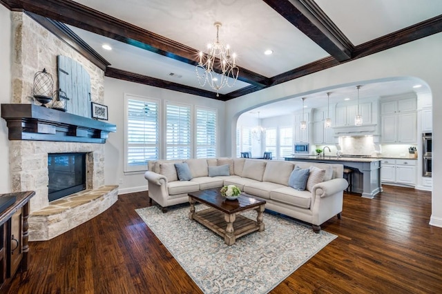 living room featuring baseboards, dark wood finished floors, crown molding, a fireplace, and beam ceiling