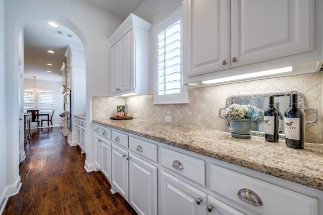 kitchen featuring tasteful backsplash, visible vents, white cabinets, dark wood finished floors, and light stone countertops