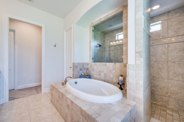 bathroom with a garden tub, tile patterned flooring, baseboards, and a walk in shower