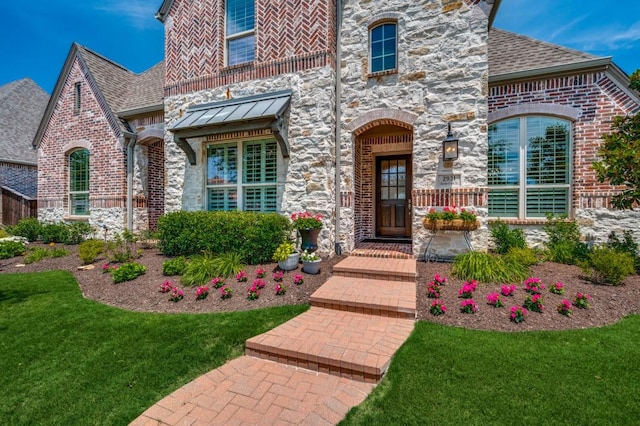 view of front of property featuring a front yard, stone siding, and brick siding