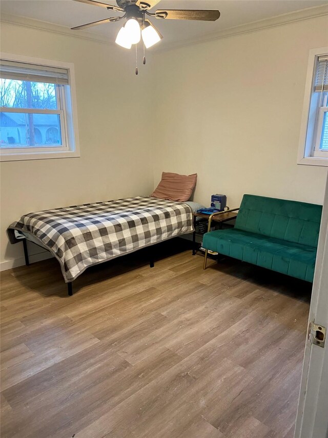 bedroom featuring ornamental molding, wood finished floors, a ceiling fan, and baseboards