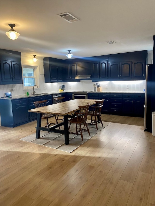 kitchen with blue cabinets, light countertops, visible vents, and a sink