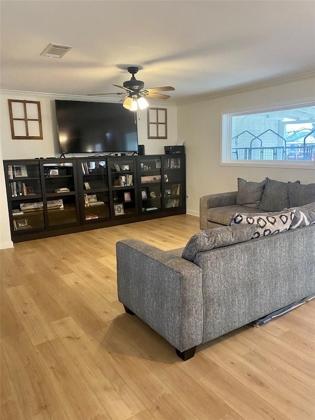 living area featuring visible vents, wood finished floors, and ornamental molding