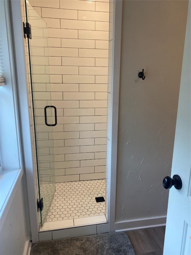 full bath featuring a stall shower, wood finished floors, and baseboards