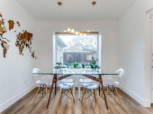 dining room with wood finished floors, baseboards, and ornamental molding