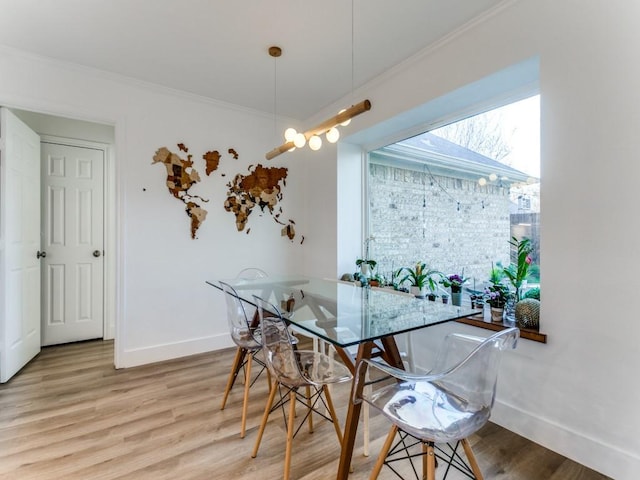 dining room featuring light wood-style flooring, baseboards, and ornamental molding