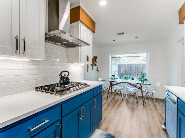 kitchen featuring blue cabinetry, visible vents, appliances with stainless steel finishes, and wall chimney range hood