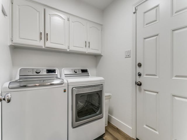 washroom featuring washer and dryer, wood finished floors, cabinet space, and baseboards