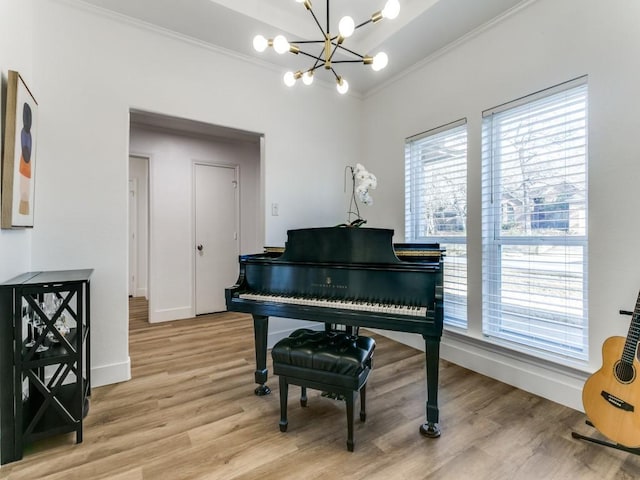 living area with an inviting chandelier, crown molding, light wood-style floors, and baseboards