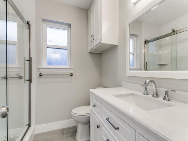 full bath with baseboards, toilet, a stall shower, wood finished floors, and vanity