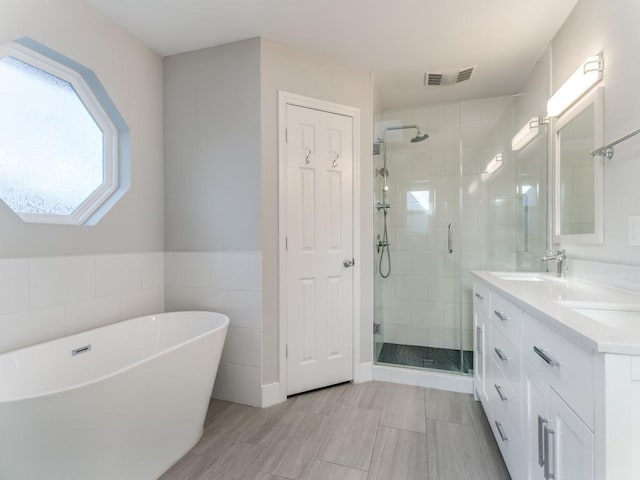 full bathroom with vanity, a shower stall, visible vents, and a freestanding bath