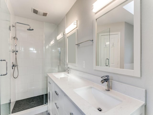 full bathroom featuring double vanity, a stall shower, and a sink