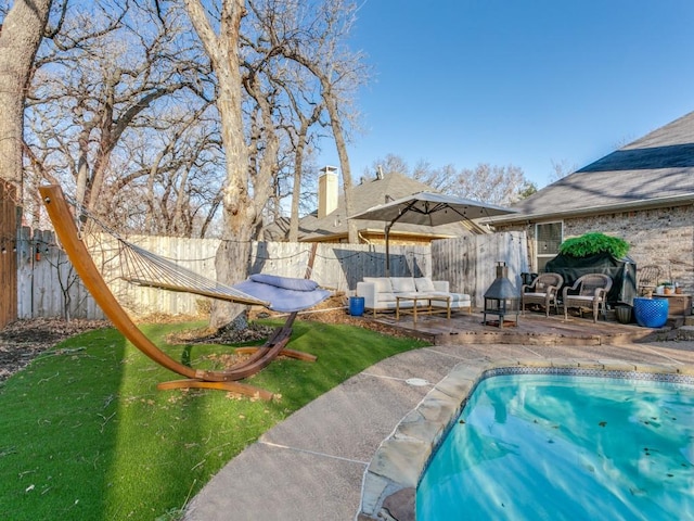 view of pool with an outdoor living space, a wooden deck, and fence