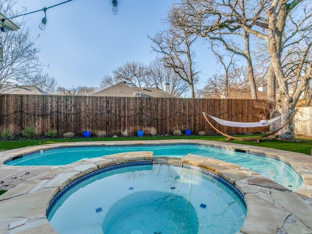 view of swimming pool featuring a fenced backyard and a pool with connected hot tub