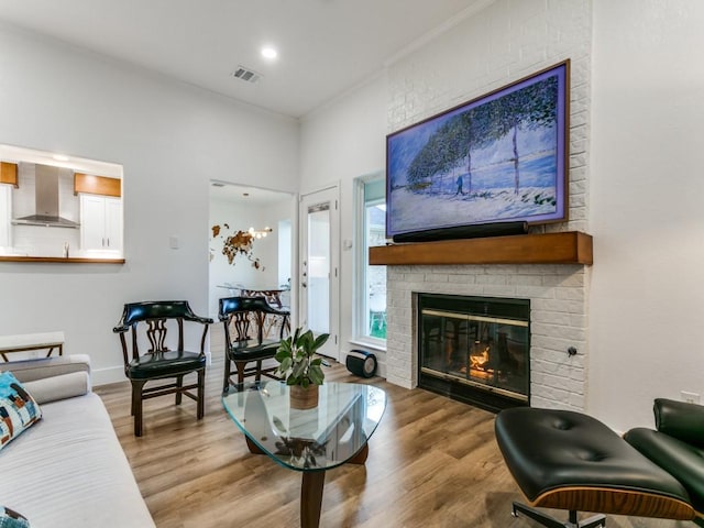 living room with visible vents, crown molding, baseboards, a fireplace, and wood finished floors