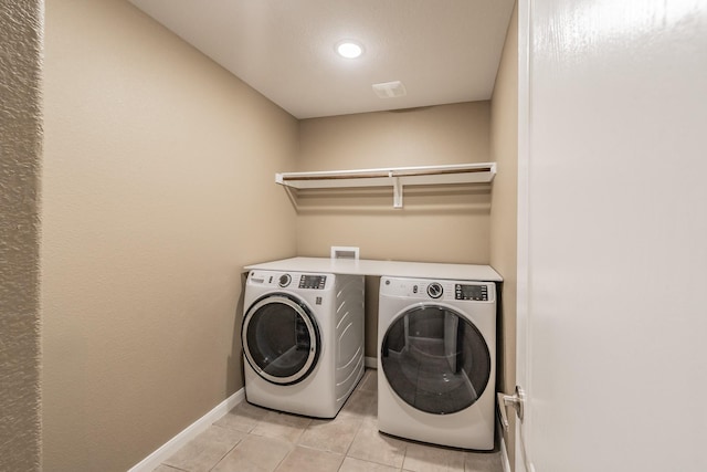 clothes washing area with washer and dryer, laundry area, baseboards, and light tile patterned floors