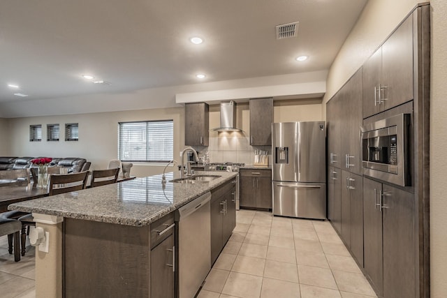 kitchen featuring stainless steel appliances, visible vents, light tile patterned flooring, a sink, and wall chimney exhaust hood