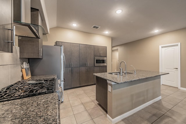 kitchen with visible vents, appliances with stainless steel finishes, a sink, an island with sink, and dark brown cabinets