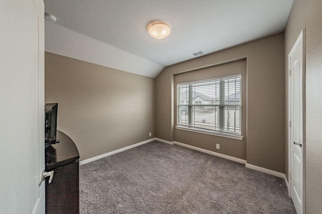 unfurnished bedroom with lofted ceiling, carpet floors, baseboards, and visible vents