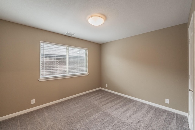 unfurnished room with carpet, visible vents, and baseboards