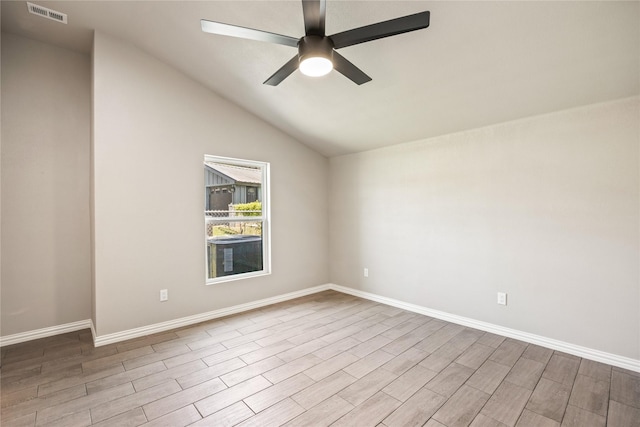 empty room with visible vents, vaulted ceiling, ceiling fan, wood finished floors, and baseboards