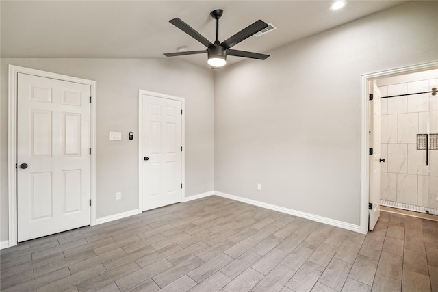 unfurnished bedroom featuring lofted ceiling, wood tiled floor, baseboards, and connected bathroom