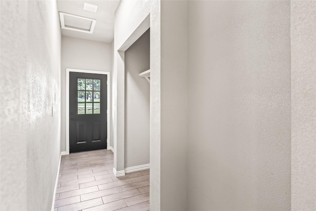 entryway with wood finish floors, a textured wall, and baseboards