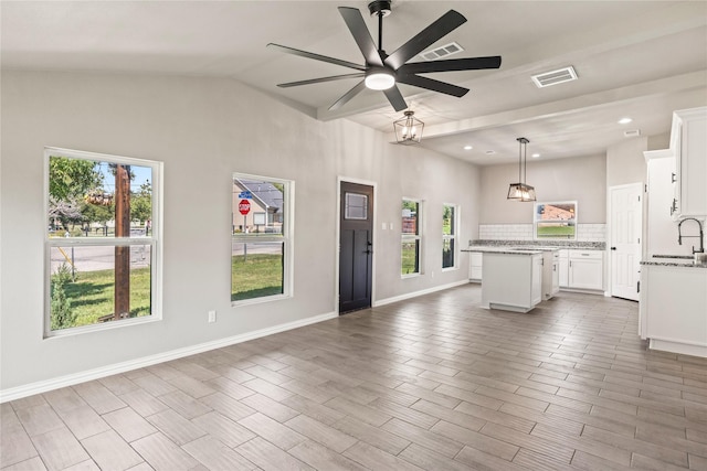 kitchen featuring visible vents, decorative backsplash, a kitchen island, open floor plan, and a sink