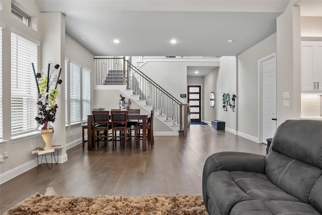 living room featuring plenty of natural light, stairs, baseboards, and dark wood finished floors