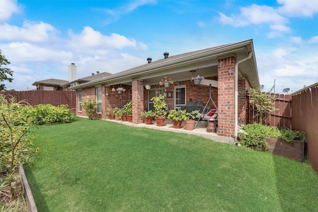 back of property with brick siding, a lawn, and a fenced backyard