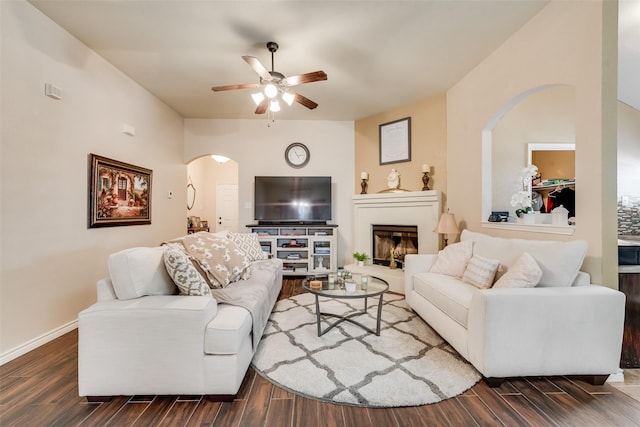 living room with wood finish floors, a fireplace with raised hearth, and arched walkways