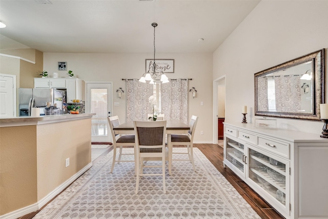 dining space featuring baseboards, a chandelier, and wood finished floors