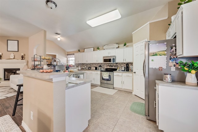 kitchen featuring tasteful backsplash, a breakfast bar, a peninsula, stainless steel appliances, and white cabinetry