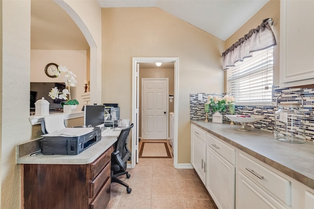 home office featuring arched walkways, vaulted ceiling, baseboards, and light tile patterned floors