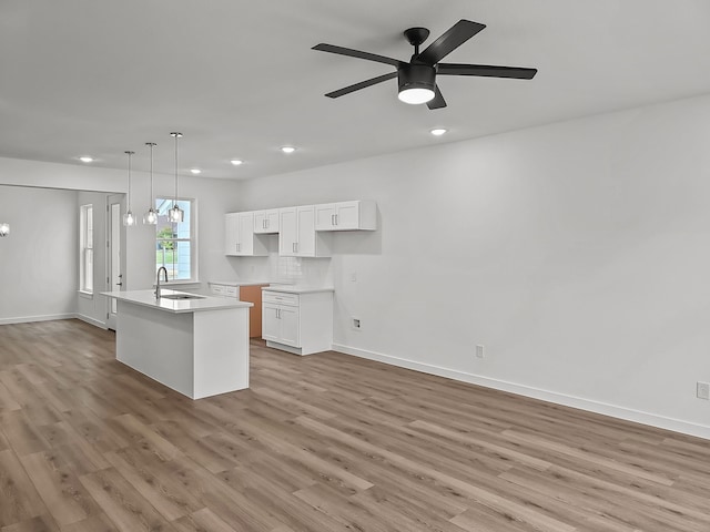 kitchen featuring light wood finished floors, a sink, white cabinetry, and tasteful backsplash