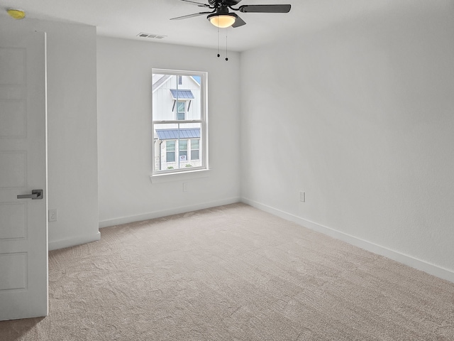 carpeted spare room with a ceiling fan, visible vents, and baseboards