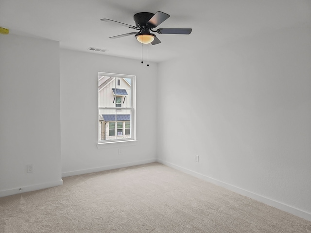 empty room with light carpet, ceiling fan, visible vents, and baseboards