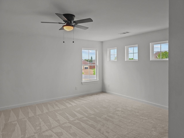 spare room featuring baseboards, visible vents, a ceiling fan, and light colored carpet