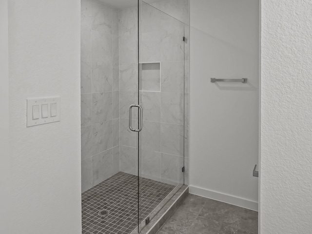 full bathroom with a shower stall and baseboards