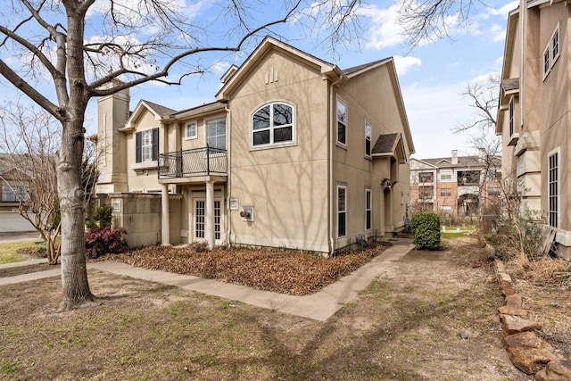 rear view of property with a balcony and stucco siding