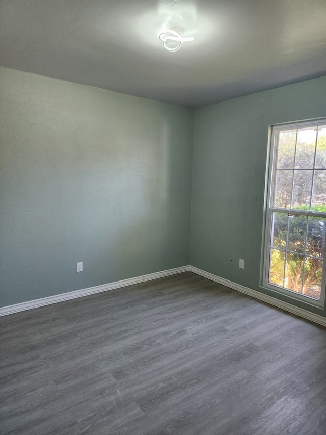 empty room with dark wood-type flooring and baseboards