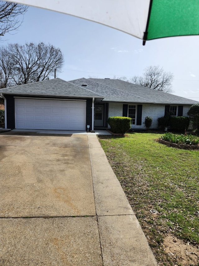 ranch-style house featuring brick siding, roof with shingles, concrete driveway, a garage, and a front lawn