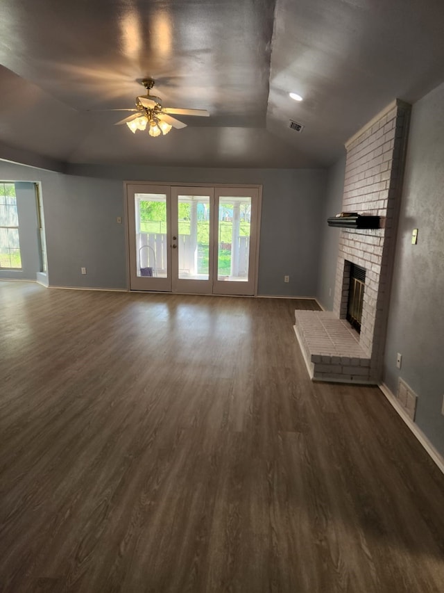 unfurnished living room featuring ceiling fan, dark wood-type flooring, visible vents, vaulted ceiling, and a healthy amount of sunlight