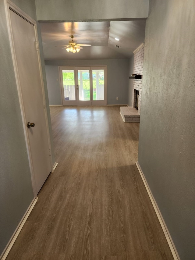 hallway with baseboards, vaulted ceiling, and wood finished floors