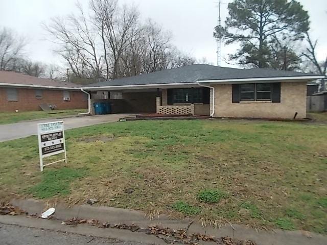 ranch-style home featuring concrete driveway and a front yard