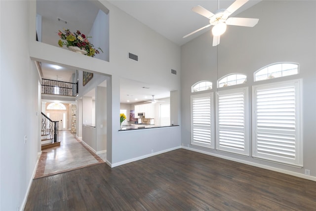 empty room with ceiling fan, stairway, dark wood finished floors, and baseboards