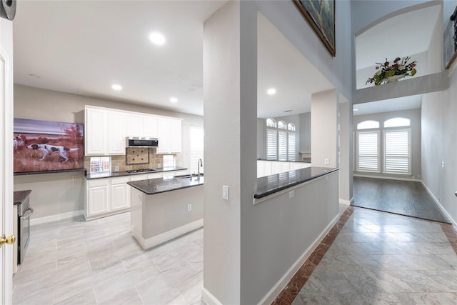 kitchen featuring baseboards, decorative backsplash, appliances with stainless steel finishes, white cabinetry, and recessed lighting