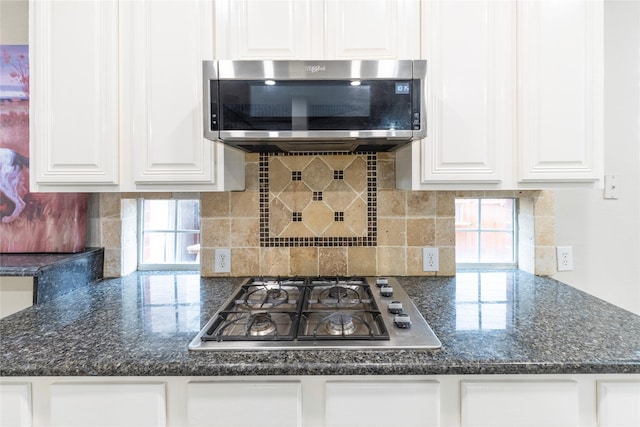 kitchen with tasteful backsplash, white cabinetry, stainless steel appliances, and dark stone counters