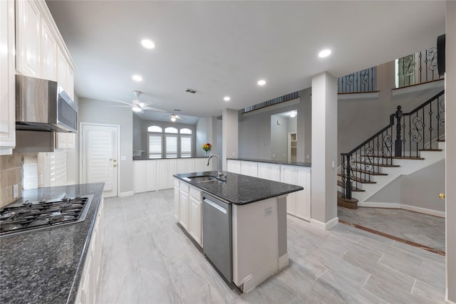 kitchen featuring a center island with sink, tasteful backsplash, appliances with stainless steel finishes, white cabinetry, and a sink