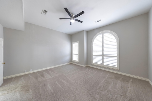 carpeted empty room featuring ceiling fan, visible vents, and baseboards